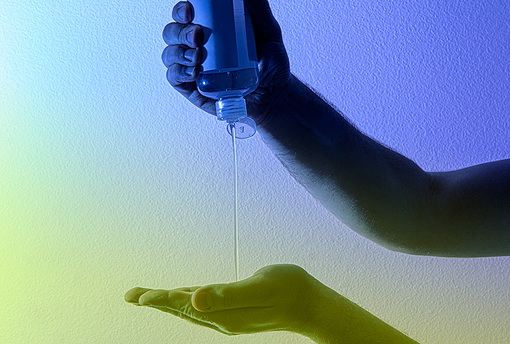 A man squeezes sunscreen out of a bottle and into the palm of his other hand. 