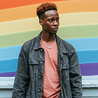 A person standing in front of a rainbow graphic.