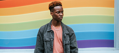 A person standing in front of a rainbow graphic.