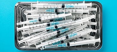 A tray of needles sits against a blue surface.
