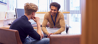 A PrEP counselor smiles as he talks with a young man in his office.