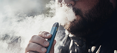 A man blows out smoke after using an e-cigarette.