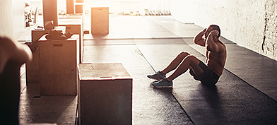 ThumbA man is doing sit-ups in the gym with sunlight shining through the window.