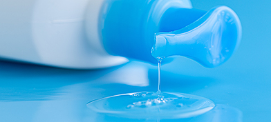 Blue-lube-bottle-lying-down-with-lube-leaking-onto-a-blue-surface