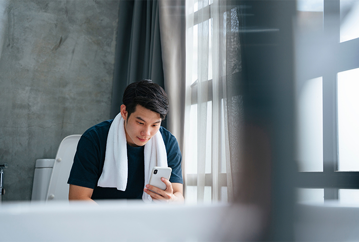 A-man-sits-on-the-toilet-looking-at-his-phone