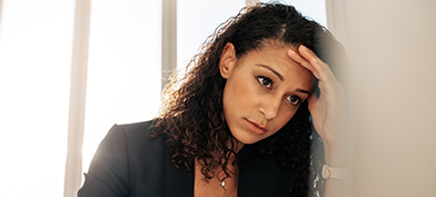 A stressed woman leans her head into her hand.