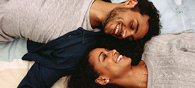 A-man-and-woman-are-laying-next-to-each-other-smiling
