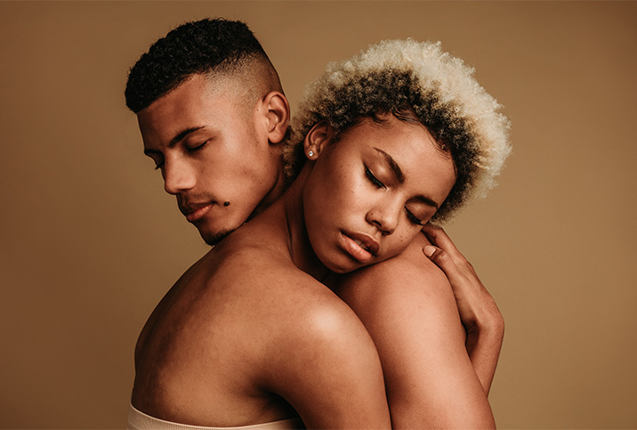 A naked couple embraces with their eyes closed.
