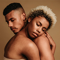 A naked couple embraces with their eyes closed. 