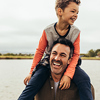 A-child-sits-on-hist-dads-shoulders-and-both-laugh