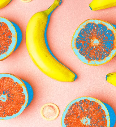 Bananas and open grapefruit are spread amongst condoms.
