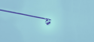 A needle has a little drop of liquid on the end holding a baby.