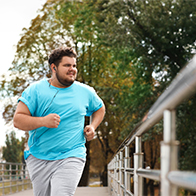A man runs down the street, wearing blue and listening to music.