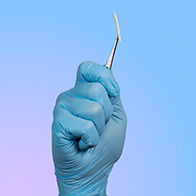 A hand inside of a surgical glove holds a birth control implant between a pair of tweezers.