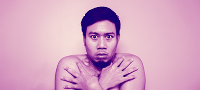 A man covers his body with his arms looking scared.