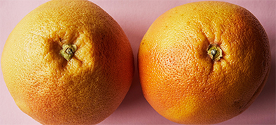 Two oranges sit side by side, resembling breasts. 