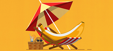 A banana lays in a beach chair underneath an umbrella and next to a picnic basket.