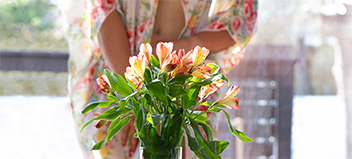 A bunch of flowers are centered in the frame with a blurred woman holding them in the background.