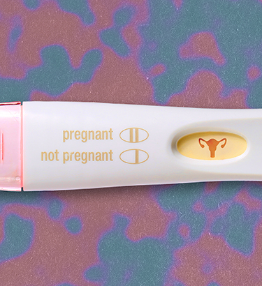 A pregnancy test with an icon of the female reproductive system is against a red and purple background.