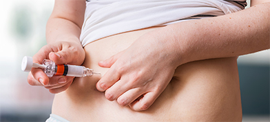 A woman injects fertility hormones inter her hip with a needle.