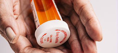 A pair of hands are holding an empty pill bottle.