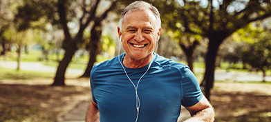 A man smiles while jogging and listening to music.