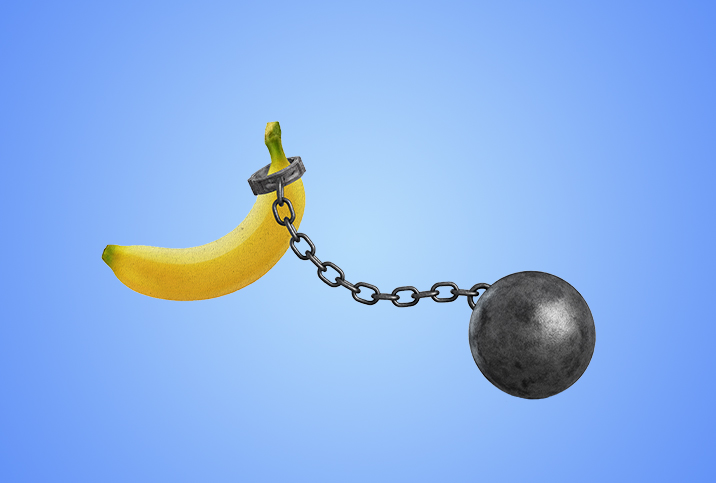 A ball and chain is linked on the end of a banana against a blue background.
