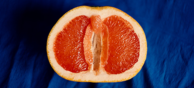 Half of a grapefruit sits open-faced against a blue cloth.