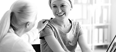 A woman with a headwrap smiles at another woman who touches her shoulder.