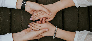 A man and woman hold hands across a wooden table.