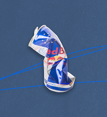 A can of Red Bull that has been squeezed and crunched is against a blue background.