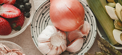 A view from above shows fruits and vegetables sit in bowls on a table.
