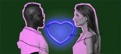 A couple stand across from each other with a neon heart light heart between them.