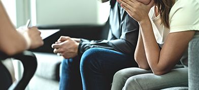 A woman sits next to a man on a couch with her hand in her hands.