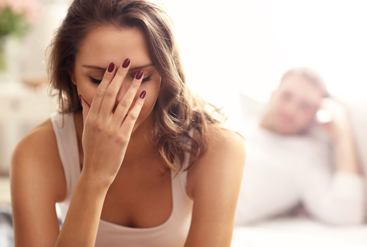 A woman closes her eyes as she holds her face with her right hand.