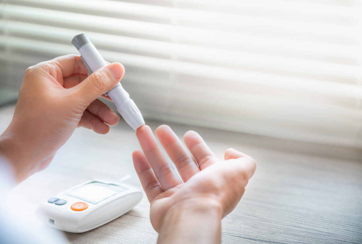 A person uses a lancet to prick their ring finger.
