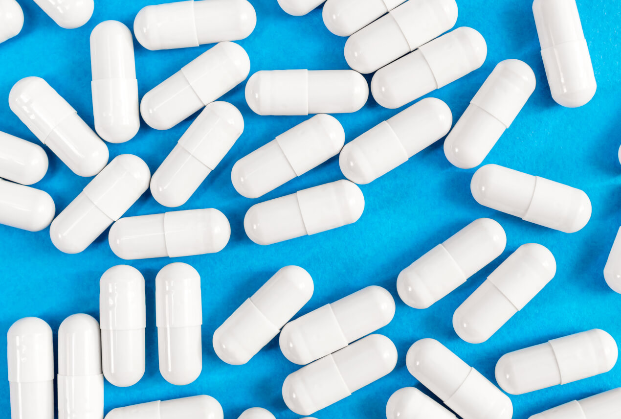 White pills are scattered on a blue surface.