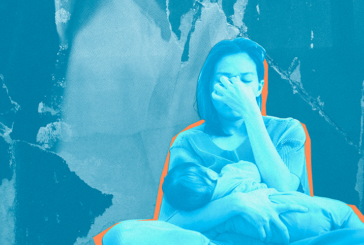 A woman holds her newborn against her chest as she holds the bridge of her nose.