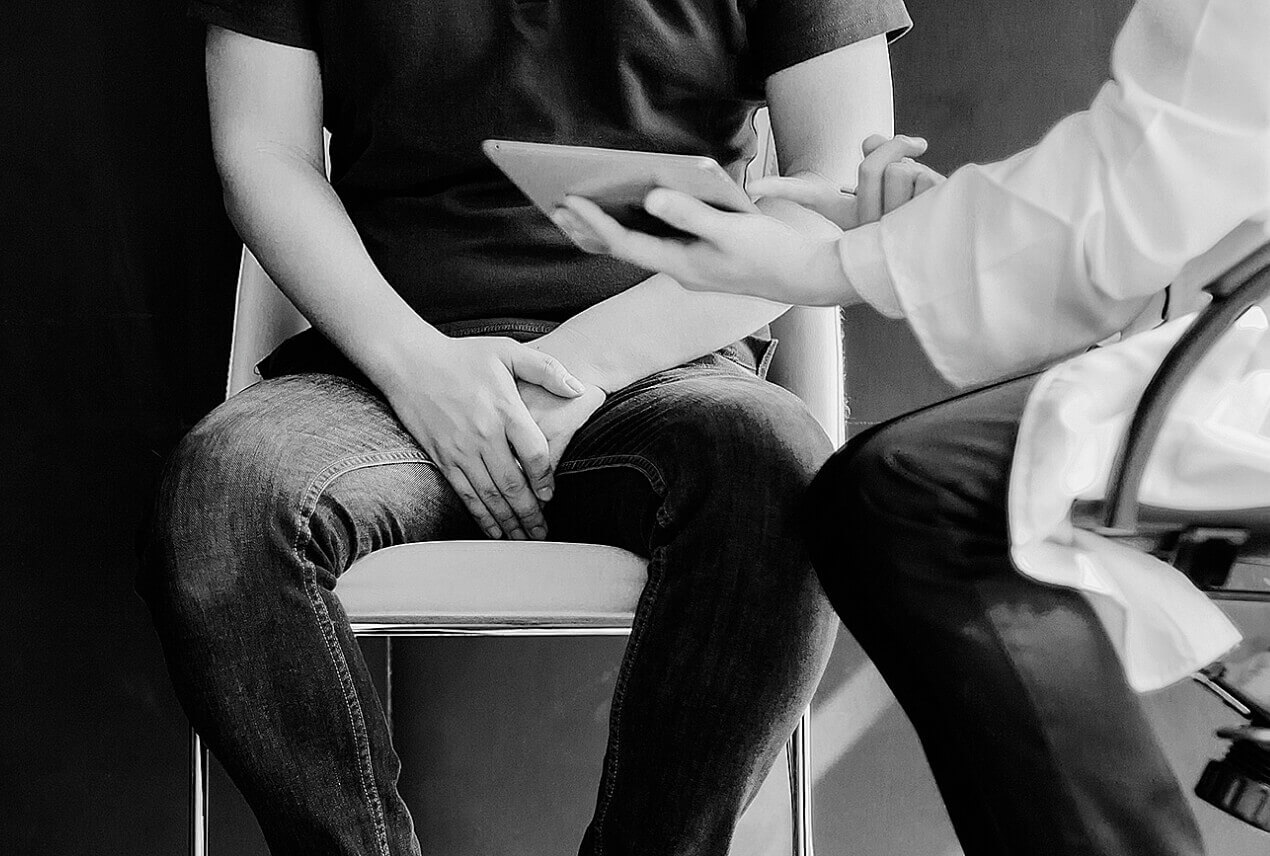 A doctor expressively speaks with a man in a folding chair.