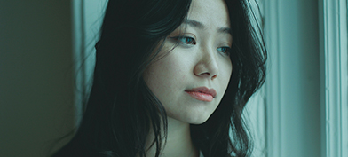 A green-ish filter covers an image of a woman looking out a window.