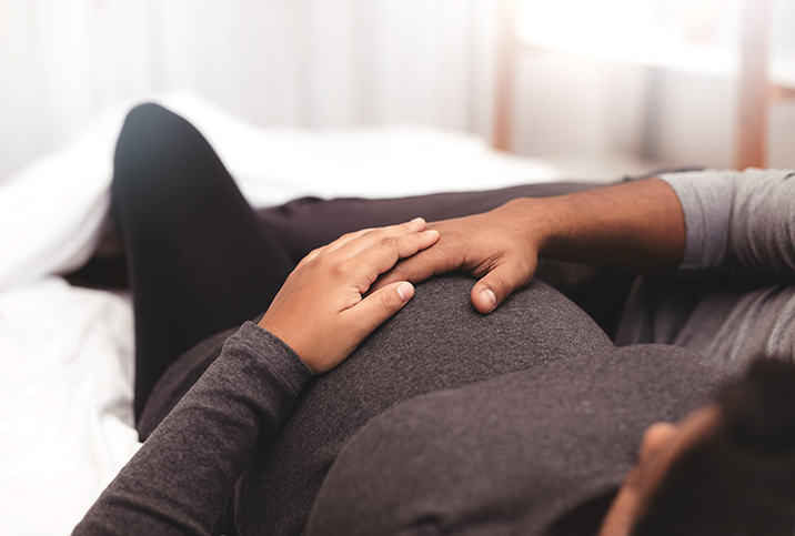 A pregnant person and their partner touch the baby bump.