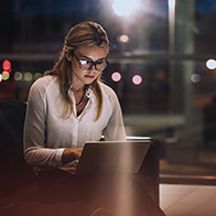 A woman works on her laptop in a coffeeshop at night.