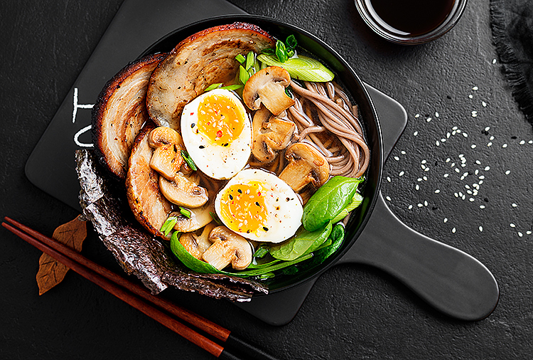 A pan with eggs and vegetables sits on a black counter.