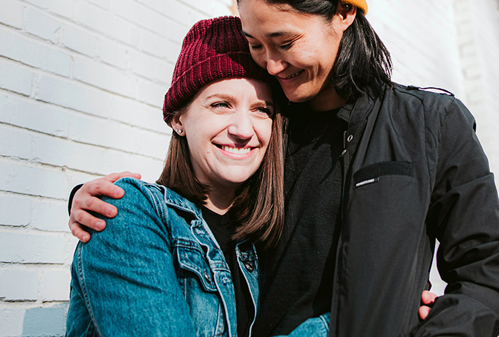 One woman has her right arm wrapped around another woman who is smiling.