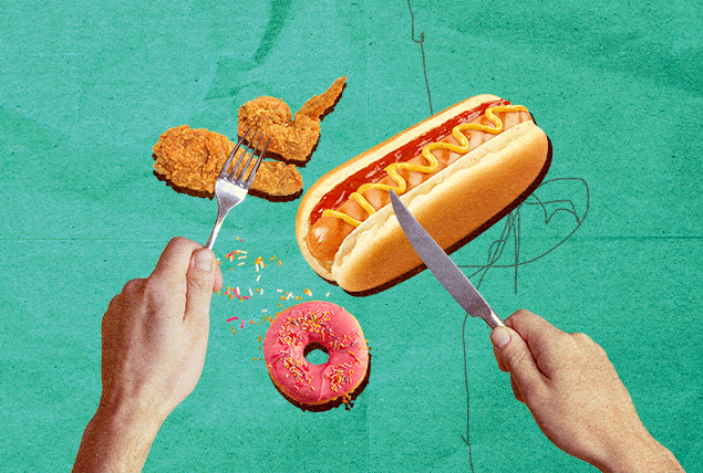 A pair of hands hold a knife and fork over several different foods.