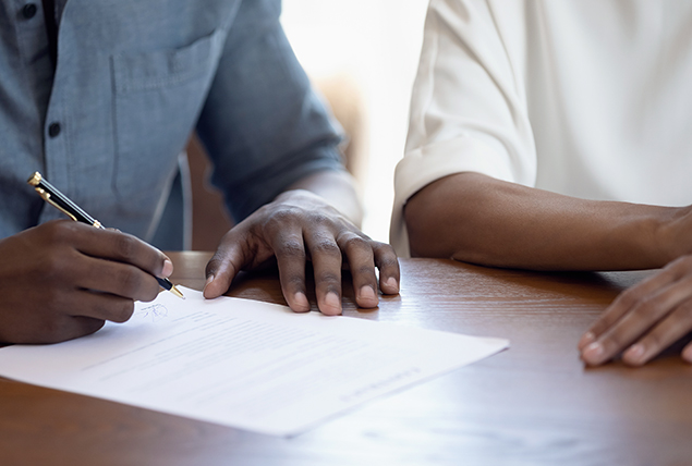 A couple signs a postnuptial agreement.