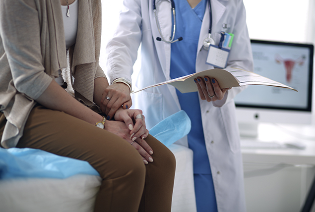 woman sits in doctors office and is comforted by doctor in white coat