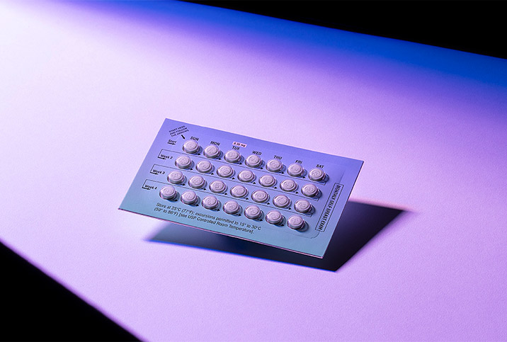 a sleeve of birth control pills on a purple background