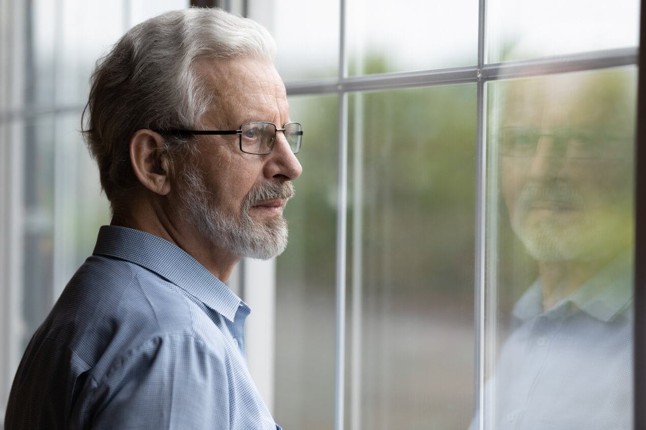 An older man looks out of the window.