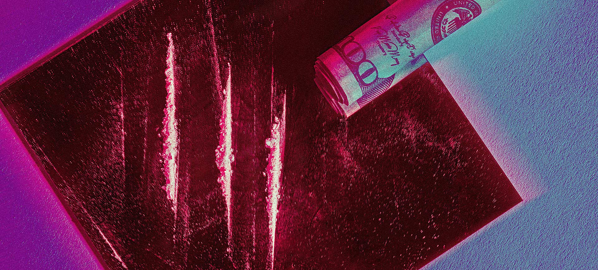 lines of white powder on mirror with rolled up dollar bill in neon red lighting